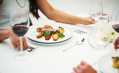 Image showing Couple, table and food at restaurant in closeup for valentines day date, bonding or romance in night. Man, woman and red wine glass with fine dining, service and hands for dinner, love or celebration