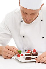 Image showing Cook, dessert and mint on sweet chocolate or berries on food by culinary chef with recipe on a plate in white studio background. Cooking, presentation and man or person making mini cakes as cuisine