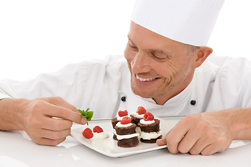 Image showing Baking, smile and chef with a dessert for catering isolated on a white background. Cooking, professional and man plating a chocolate cake and fruit on a plate for a food service on a backdrop