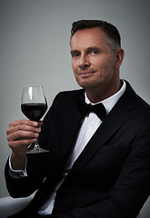 Image showing Tuxedo, red wine and man portrait with alcohol in a suit feeling classy with a luxury drink. Gray background, isolated and studio with a model, agent or actor with a glass of rich person with mockup