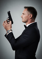 Image showing Agent man, profile and gun with suit for mission, justice or espionage by grey studio background. Government spy, detective and firearm with designer tuxedo, secret information and undercover work