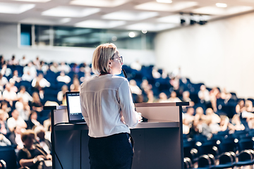 Image showing Female speaker giving a talk on corporate business conference. Unrecognizable people in audience at conference hall. Business and Entrepreneurship event.