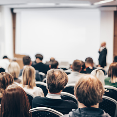 Image showing Speaker giving a talk in conference hall at business event. Rear view of unrecognizable people in audience at the conference hall. Business and entrepreneurship concept.