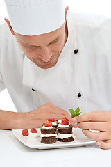 Image showing Chef, dessert and mint on sweet food by culinary cook with chocolate recipe on a plate isolated in white studio background. Cooking, presentation and man making mini cakes as cuisine for fine dining