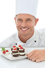 Image showing Man, face and chef, dessert in portrait and smile, baker skill and cake presentation isolated on white background. Happy person, chocolate and fruit for Valentines day plate and hospitality in studio