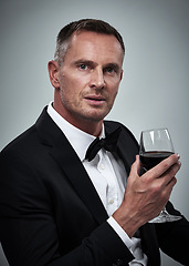 Image showing Tuxedo, red wine and spy man with alcohol in a suit feeling classy with a luxury drink. Gray background, isolated and studio with a model, agent or actor with a glass and rich person with mockup