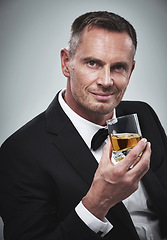 Image showing Portrait, man and a glass of whisky for celebration, smile and guy on grey studio background. Face, male and gentleman in a suit, alcohol beverage or drinking for achievement, confidence or happiness