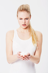 Image showing Confused, shocked and woman holding pills in her hands or overdose isolated against a studio white background. Medicine, capsules and annoyed female with tablets due to mental health issues