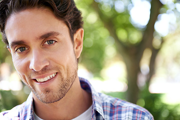 Image showing Happy, portrait and man at a park for travel, relax or day off, cheerful and smile on nature background. Face, real and normal guy enjoying the weekend in a forest, content and satisfied in nature