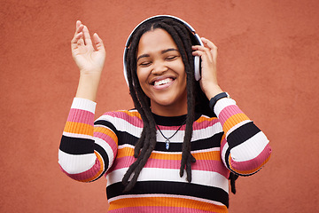 Image showing Black woman, music headphones and wall with smile in city for walk, adventure and listening to edm on radio. Young gen z girl, streaming hip hop or techno on website, internet and happiness in metro