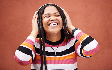 Image showing Black woman, music headphones and happy by wall in city for walk, adventure and me time with smile. Young gen z girl, audio streaming and excited listening on radio, website and happiness in metro