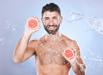 Image showing Grapefruit, water splash and man on blue background for wellness benefits, beauty and skincare. Male model, portrait and citrus fruits for vitamin c cosmetics, detox and nutrition for healthy shower