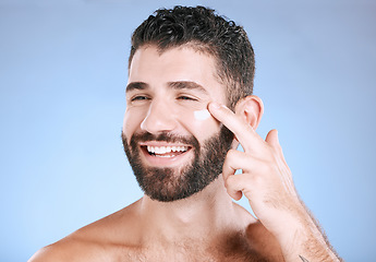 Image showing Face, cream and man laughing for beauty, sunscreen product and clean wellness on blue background. Happy male model, facial lotion and body cosmetics for natural skincare, studio aesthetics and smile