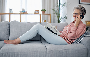 Image showing Phone call, reading and relax on the sofa with a senior woman in the living room of her home over the weekend. Mobile, books and retirement with a mature female sitting on a couch in the lounge