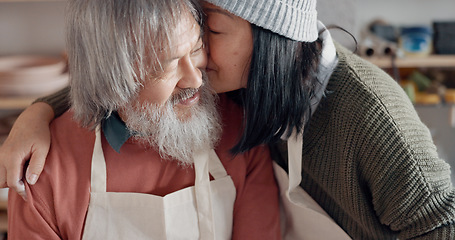 Image showing Pottery, creative and senior couple talking about art with hug and kiss together in a studio class. Elderly Asian man and woman hugging with love while learning and working with clay on a date