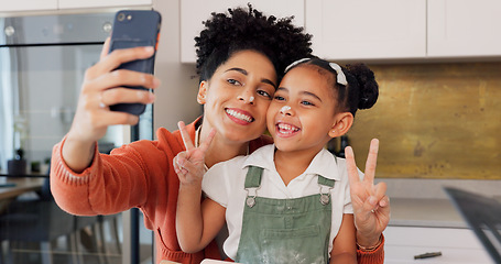 Image showing Mother, girl and phone selfie while cooking in kitchen, bonding and having fun. Learning, baking and mom, kid and 5g mobile for social media, picture or online post with victory hands or peace sign