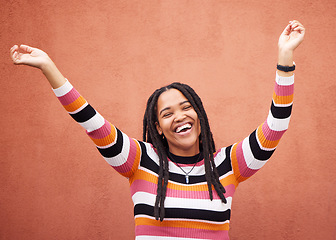 Image showing Celebration, energy and woman by a wall in the city on a walk while on a holiday or weekend trip. Happiness, smile and African female celebrating with freedom in urban town on a vacation or adventure