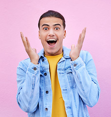 Image showing Man, hands and face for surprise in portrait with happiness, excited and pink wall background. Happy gen z model, wow and smile for announcement, fashion and news for career, success and life goal
