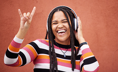 Image showing Rock sign, headphones and black woman isolated on orange wall for gen z music subscription or mental health. Young person or excited youth listening to audio 5g technology or streaming services