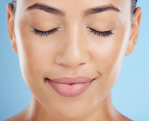 Image showing Face, woman and makeup in studio for beauty, skincare and grooming against a blue background space. Glamour, headshot and girl model relax in luxury cosmetic, skin and natural, wellness and treatment