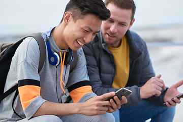 Image showing Asian man, phone and friends by the sea happy about mobile connection and travel. Technology, social media scroll and ocean with men streaming a video with 5g network outdoor with happiness together