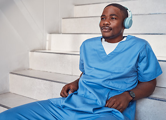 Image showing Break, music and African doctor with headphones for a podcast, radio and audio on hospital stairs. Freedom, thinking and a male nurse listening to a track or songs while working in healthcare