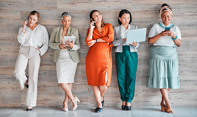 Image showing Wall, business and women with devices, online reading and connection for social media, typing and communication. Diversity, female employees and happy coworkers chatting, texting and search internet