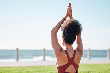 Image showing Fitness, black woman and yoga meditation by beach for spiritual wellness or exercise in nature. Sporty female yogi back in warm up arm stretch for zen workout, relax or meditating by ocean coast