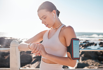 Image showing Fitness time, smartwatch and woman with headphones checking running goals by the sea. Ocean, exercise app and workout timer with a runner by ocean water in summer after run and sports by a beach