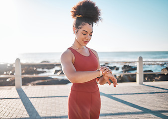 Image showing Fitness, black woman and watch checking by beach for time, performance or tracking exercise in the outdoors. Happy African American female runner smiling looking at wristwatch for monitoring workout