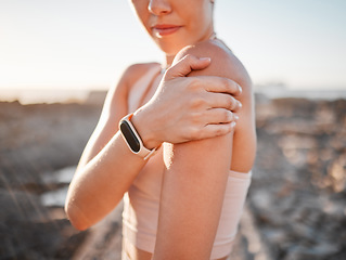 Image showing Beach, fitness and woman with hand on shoulder pain standing on rocks at ocean. Nature, sports and injury during workout for health and wellness, muscle trauma during stretching exercise in morning.