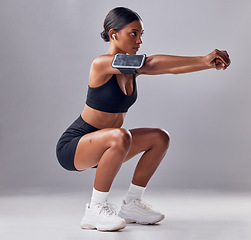 Image showing Black woman, studio background and squat training for fitness, smartphone and strong legs, muscle or mind. Gen z girl, personal trainer and phone with vision, motivation or mindset for anatomy goal