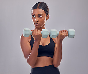 Image showing Woman, focus and dumbbell training in studio for strong body, action or thinking of mindset goals. Indian female, bodybuilder and weights of fitness, power exercise or muscle energy of sports workout