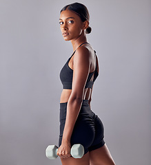 Image showing Woman, focus portrait and dumbbell in studio for strong body, wellness power or healthy workout goals. Indian female, bodybuilder and weights of fitness, training and muscle energy in sports exercise