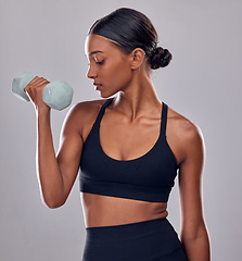 Image showing Black woman, dumbbells exercise and studio for muscle development, wellness and self care with focus. Gen z bodybuilder girl, training and strong healthy body with gym equipment by gray background
