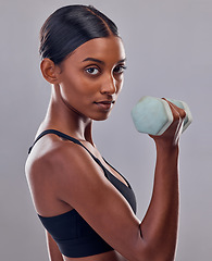 Image showing Woman, portrait and bicep with dumbbell in studio for strong body, action and focus exercise. Indian female, bodybuilder and weights of fitness, power training and muscle energy for sports workout