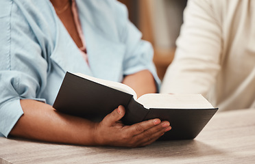 Image showing Hands, bible and books with a senior couple reading a book together in their home during retirement. Jesus, faith or belief with a man and woman praying to god in their house for spiritual bonding