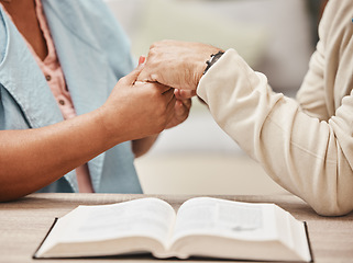 Image showing Hands, bible and pray with a senior couple reading a book together in their home during retirement. Jesus, faith or belief with a man and woman praying to god in their house for spiritual bonding