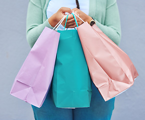 Image showing Fashion, hands or black woman with shopping bag or gift on promotion in retail therapy against wall. Freedom, relaxing or girl on holiday vacation with clothes or products on discounted sales offer