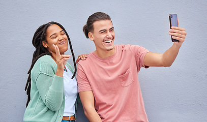 Image showing Young happy couple, selfie and smile by wall with phone, profile picture and happiness in city. Influencer, man and black woman with smartphone, social media and peace sign by background in metro