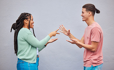 Image showing Couple playing rock, paper, scissors by a wall in the city for game, decision or choice while on holiday. Playful, happy and interracial and woman having fun together in town while on a vacation.