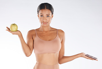 Image showing Black woman, studio and portrait for apple, chocolate and decision for health, body and nutrition by background. Gen z model, underwear or choice for diet, fruit or candy for thinking of cheat day