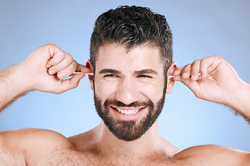 Image showing Cleaning, ear and man with cotton bud in studio for hygiene, grooming and beauty routine on blue background. Earwax, product and guy model in cosmetic, luxury and wax, removal or stick while isolated