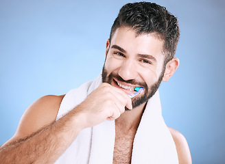 Image showing Toothbrush, portrait and man brushing teeth in studio for dental wellness, healthy smile and mouth. Happy male model, oral care and fresh breath for gums, dentistry and hygiene on blue background