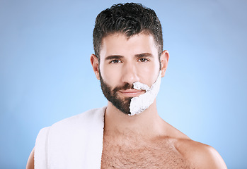 Image showing Portrait of man with foam on half beard, with towel and skin product placement in studio mock up. Shaving cream on face, hair and skincare for happy male model grooming, isolated on blue background.