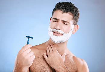 Image showing Shaving, beard and confused man with razor in hand, foam product placement in studio mock up. Shave accident, cream on face and hair or skincare for male model grooming, isolated on blue background.