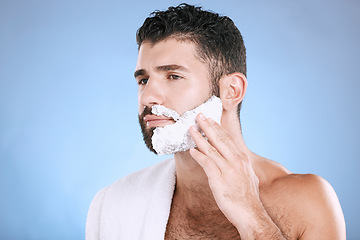 Image showing Facial, man putting foam on beard with hand on face, towel and product placement in studio mock up. Shaving cream, hair and skincare for male model grooming, isolated on blue background with space.