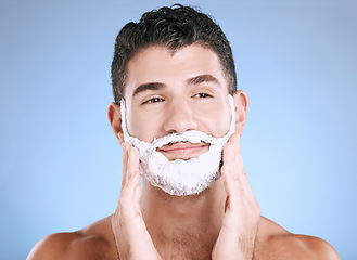 Image showing Shaving, foam on beard and man with hands on face, smile and product placement in studio mock up. Shave cream facial, hair and skincare for happy male model grooming, isolated on blue background.