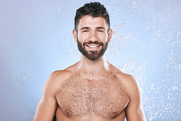 Image showing Water splash, portrait and man in studio skincare, wellness and cleaning on blue background. Face, shower and happy male model relax in luxury, gentle and moisture for beauty, cosmetics or treatment