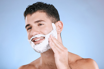 Image showing Shaving, foam on beard and man with smile and hand on face, product placement and mock up in studio. Shave cream, hair and skincare for happy male model facial grooming, isolated on blue background.